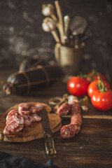 Slices of salami with tomatoes on a cutting board on a wooden table. Selective focus..
