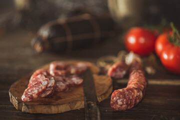Slices of salami with tomatoes on a cutting board on a wooden table. Selective focus..