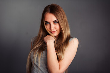 A girl with blue eyes looks piercingly into the frame, wrapping her hair in a gray background