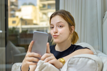 Fototapeta na wymiar Teenage girl taking a selfie with duck face at home.