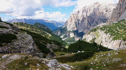 Fototapeta na wymiar Landscape of dolomite Italian Alps, overgrown with green vegetation. On a summer day. Cloudy sky