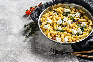Fusilli pasta with spinach and ricotta cheese ia a pan. Gray background. Top view. Copy space