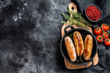 Tasty homemade sausages in a skillet. Pork, beef and chicken meat.  Black background. Top view. Copy space