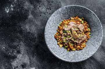 Obraz na płótnie Canvas Chinese wok fried rice with vegetables and beef. Black background. Top view. Copy space