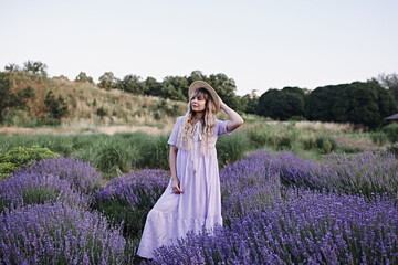 Beautiful woman on sunrise in lavender field. Provence. Young woman alone in field of flowers in the morning. 