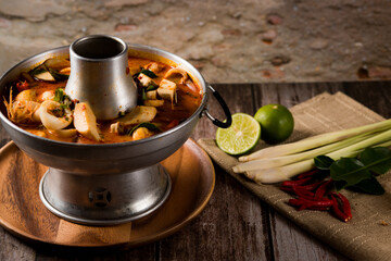 A delicious seafood soup of Thai people in a hot pot on a black background. Seafood Tom Yum with Coconut Milk