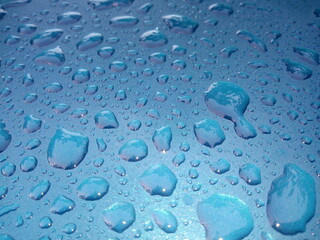 Water drops on the roof of the blue car as a background