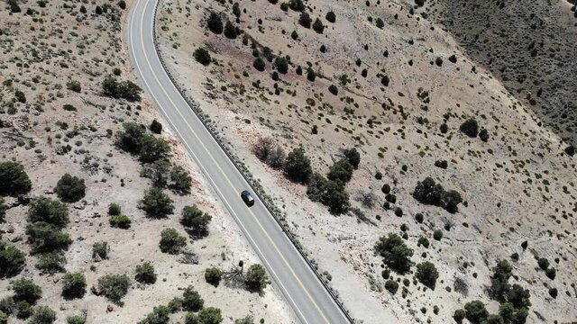 Drone Geiger grade NV tilt up follow car traffic on mountain road in the desert 