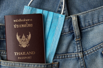 Tourism and traveling concept in New Normal after Covid-19 / Coronavirus pandemic. 
Thai Passport travel with blurred medical mask and  in jeans pocket with copy space.