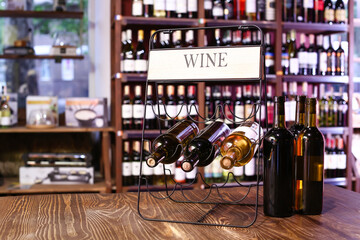 Holder with bottles of wine on table in store