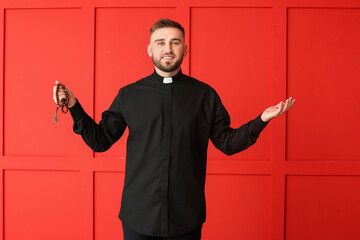 Naklejka premium Handsome young priest on color background