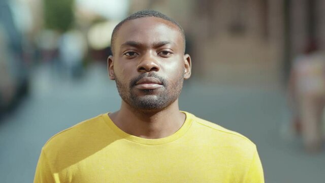 African american man raises his head looking at camera serious stand on street in city attractive face confidence handsome young sunny day portrait close up slow motion