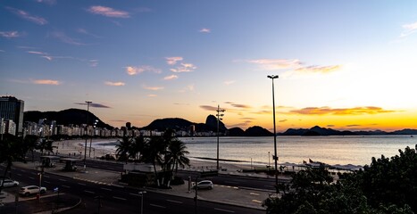 Beautiful view of the buildings and hills on the shore of the sea during sunset in Brazil