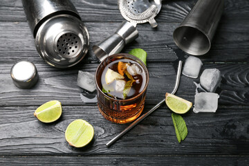 Glass of tasty Cuba Libre cocktail and ingredients on table