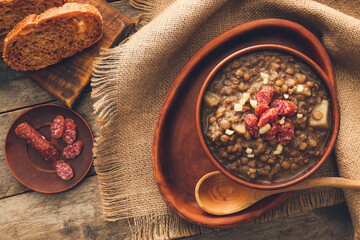 Bowl of tasty lentils soup with bread on table