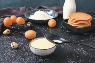 Fresh dough for pancakes on dark background