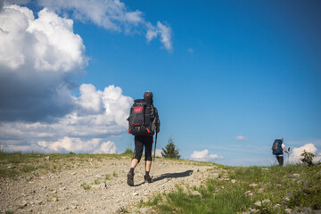 two hikers follow a path, the blue sky on the horizon. Hiking travel outdoor concept panoramic view