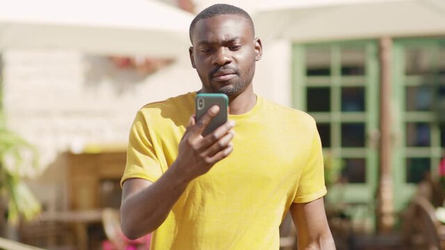 Close up african american young attractive man look at phone feel scared walk on street smile sunlight sunset black city mobile slow motion