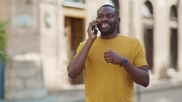Handsome african american attractive man speak on phone stand on street smile sunlight sunset cellphone fashion internet face outside technology slow motion