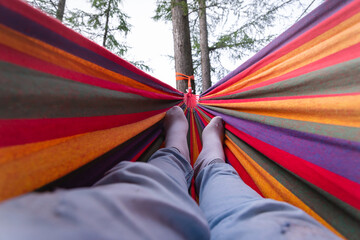 the feet of a man resting on a hammock.