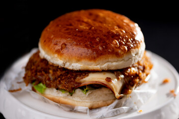 Foto em detalhe de um hamburguer com carne, queijo, molho.