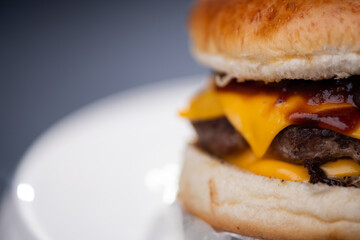 Foto em detalhe de um hamburguer com carne, queijo, molho.