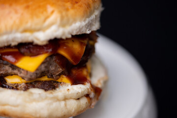 Foto em detalhe de um hamburguer com carne, queijo, molho.