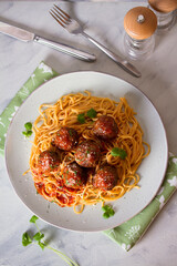 Meatballs and pasta with tomato sauce on plate. Overhead vertical image
