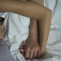 Couple holding hands while sleeping on the bed