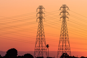 Sunset view of high voltage electricity towers on the shoreline of San Francisco bay area; California