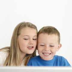 Boy and girl smiling while using laptop