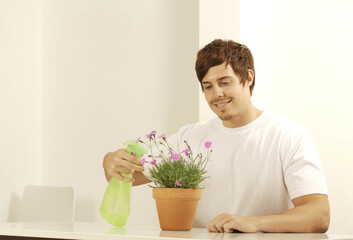 Man spraying a potted flower