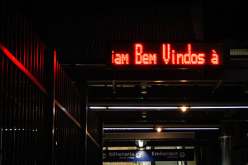 Letreiro luminoso vermelho escrito bem-vindo na entrada do metrô