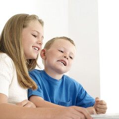 Boy and girl smiling while using laptop