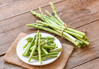 Asparagus on white plate and wooden background - Fresh green asparagus sliced for cooking food