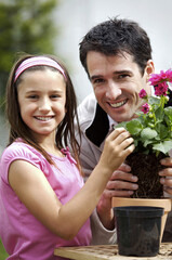 Obraz premium Man and girl planting flower into flower pot