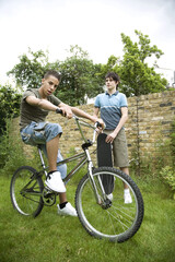 Obraz premium Boy riding on bicycle, another boy holding a skateboard