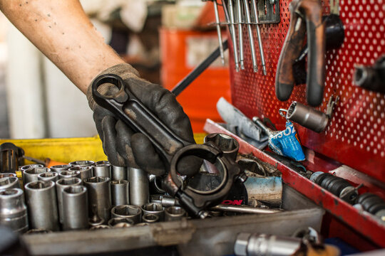 mechanic holding a connecting rod, tool board in a mechanical workshop - Powered by Adobe