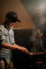 Fototapeta na wymiar キャンプで肉を焼く男性