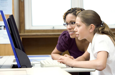Woman assisting girl using a computer