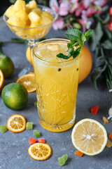 Summer fresh cold drink beverages. Ice Lemonade in the jug and lemons and orange with mint on the table outdoor. Orange lemonade in a glass