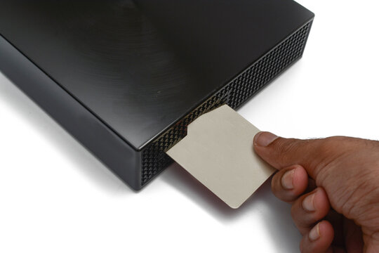 Isolated image of a man hand is inserting satellite television smart card into the decoder over white background.