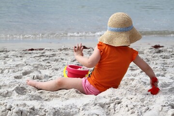 Young girl with straw hat playing on the beach