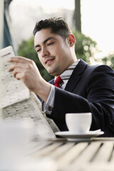 Businessman smiling while reading newspaper