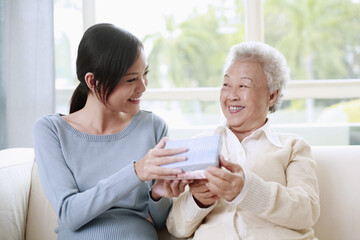 Woman giving senior woman a box of gift