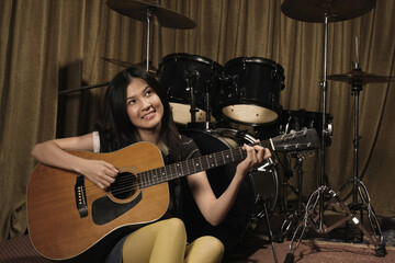 Fototapeta na wymiar Young woman smiling while playing guitar