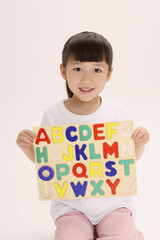 Girl holding up completed alphabet puzzle