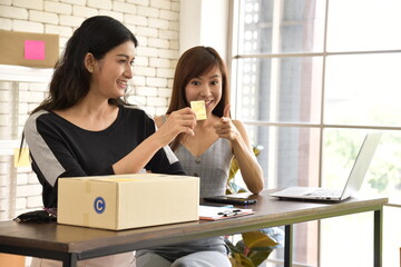 Two Asian attractive women  working with smiling at home and checking order from the customers...
