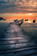 Obraz premium Wooden pontoon on a lake at sunrise or sunset