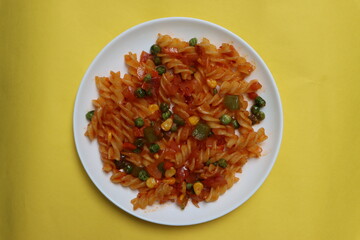 Red fusillli pasta with vegetables, corn, peas, red sauce